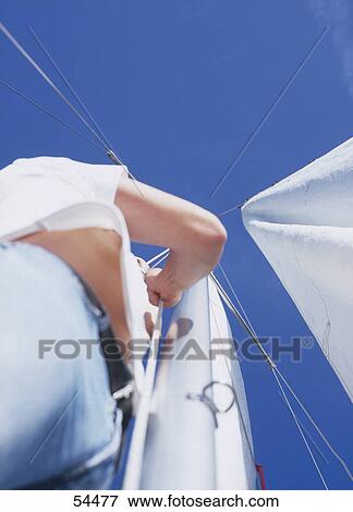 Low angle view of young woman reefing sails on sailboat View Large Photo Image Stock Photo - Low angle view of young woman reefing sails on sailboat . Fotosearch