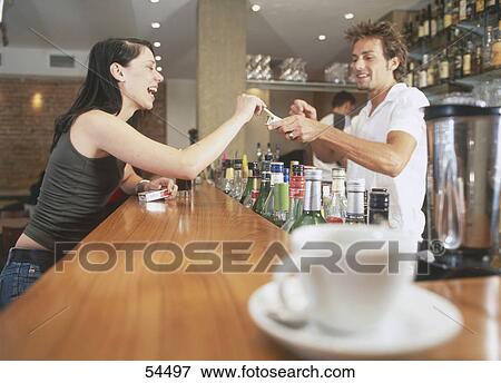 Stock Photo - Male bartender serving woman cigarette at bar . Fotosearch