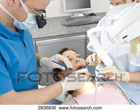 Stock Photograph - Male dentist and assistant examining patient's teeth . Fotosearch