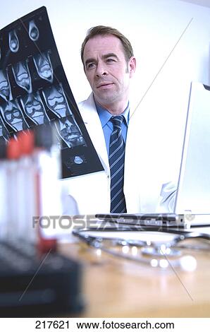 Stock Image - Male doctor looking at x-ray image . Fotosearch