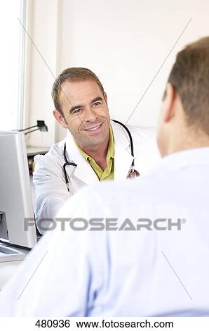 Stock Photograph - Male doctor talking to patient and smiling . Fotosearch