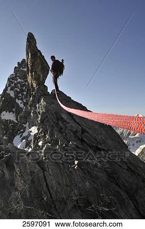 Stock Image - Male mountain hiker standing on mountain peak, Trentino-Alto Adige, Italy . Fotosearch
