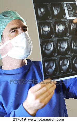 Stock Photo - Male surgeon looking at x-ray image . Fotosearch