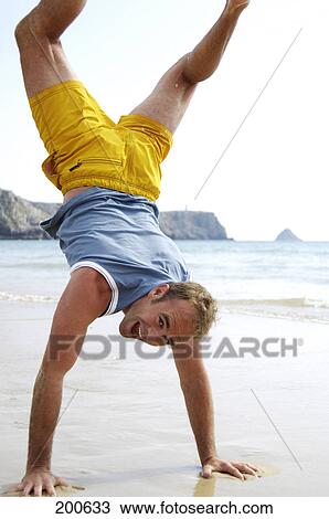 Man doing handstand at beach View Large Photo Image Stock Image - Man doing handstand at beach . Fotosearch