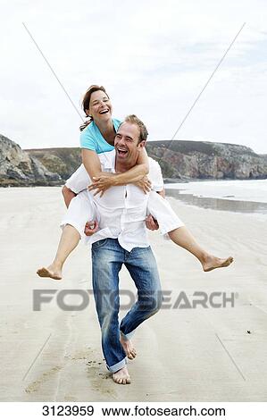 Man giving woman a piggyback ride on the beach, front view View Large Photo Image Stock Photo - Man giving woman a piggyback ride on the beach, front view . Fotosearch