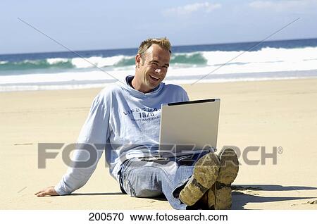 Man sitting with laptop on beach View Large Photo Image Stock Image - Man sitting with laptop on beach . Fotosearch
