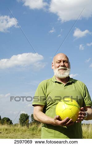 Mature man holding ball in field View Large Photo Image Stock Photo - Mature man holding ball in field . Fotosearch