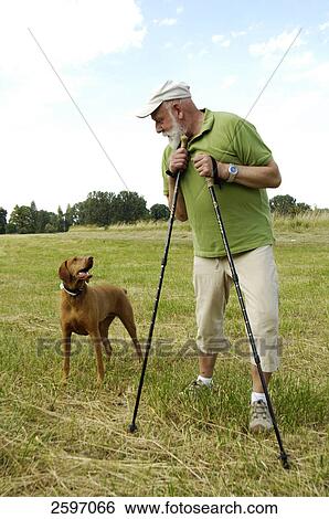 Mature man looking at dog in field View Large Photo Image Stock Photograph - Mature man looking at dog in field . Fotosearch