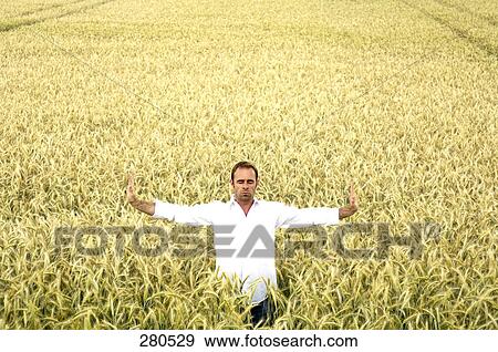 Stock Photo - Mature man standing in field with his arms outstretched . Fotosearch