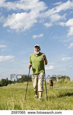 Stock Photography - Mature man walking with dog in field . Fotosearch
