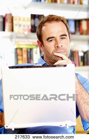Mid adult man holding laptop and thinking View Large Photo Image Stock Image - Mid adult man holding laptop and thinking . Fotosearch