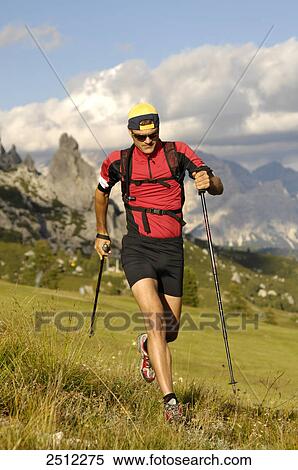 Stock Photography - Mid adult man running on landscape, Trentino-Alto Adige, Italy . Fotosearch
