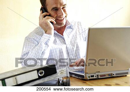 Picture - Mid adult man talking on mobile phone and smiling . Fotosearch