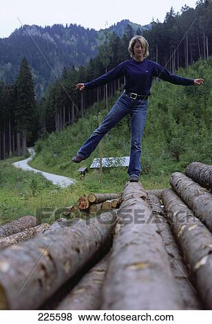 Stock Photo - Mid adult woman balancing on log . Fotosearch