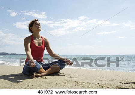 Mid adult woman meditating on beach View Large Photo Image Stock Image - Mid adult woman meditating on beach . Fotosearch