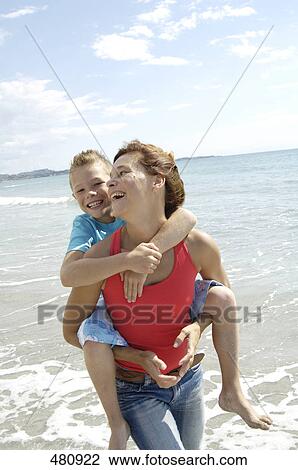 Stock Image - Mother carrying daughter piggyback . Fotosearch