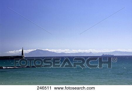 Stock Image - Panoramic view of mountain range across the sea, Straits Of Gibraltar, near Tarifa, Cadiz Province, Andalusia, Spain . Fotosearch