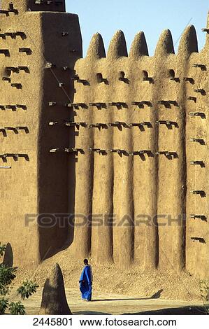 Stock Image - Person walking in front of clay mosque, Djenne, Mali . Fotosearch