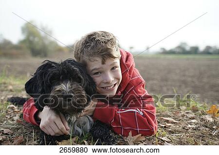 Stock Image - Portrait of boy hugging his dog and smiling . Fotosearch