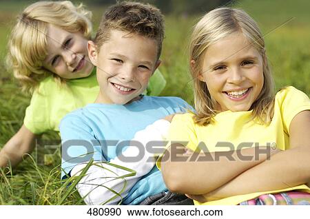 Portrait of brother and sisters smiling in field View Large Photo Image Stock Image - Portrait of brother and sisters smiling in field . Fotosearch