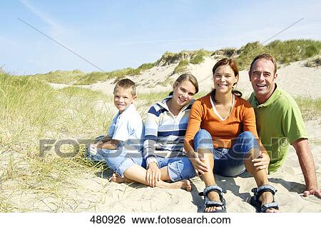 Stock Photograph - Portrait of family sitting on beach and smiling . Fotosearch