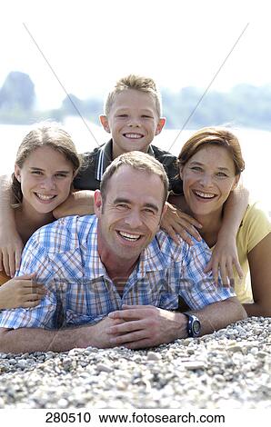Stock Image - Portrait of family smiling in field . Fotosearch