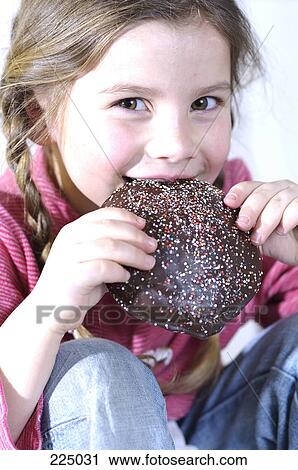 Stock Image - Portrait of girl eating gingerbread . Fotosearch