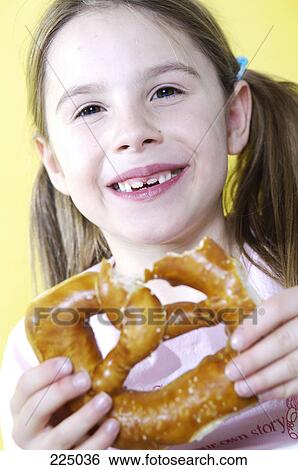 Stock Photograph - Portrait of girl eating pretzel and smiling . Fotosearch