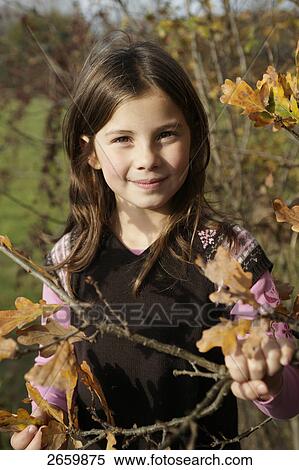Stock Photography - Portrait of girl holding twig and smiling . Fotosearch