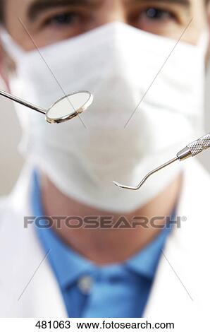 Portrait of male dentist holding plaque remover and angled mirror View Large Photo Image Stock Image - Portrait of male dentist holding plaque remover and angled mirror . Fotosearch