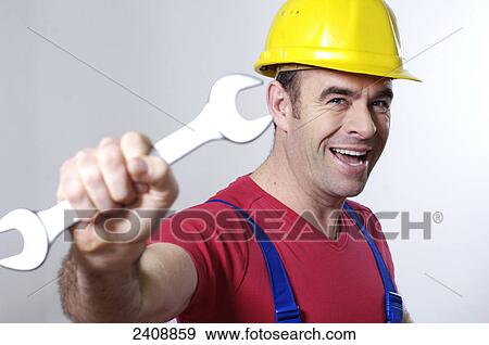 Stock Photo - Portrait of man holding wrench and smiling . Fotosearch