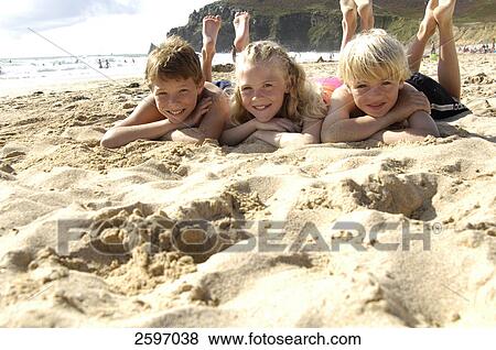 Stock Photo - Portrait of three children lying on beach and smiling . Fotosearch