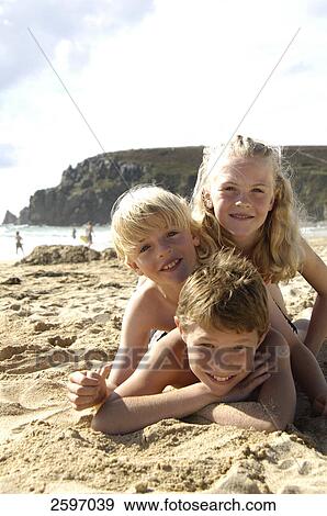 Portrait of three children lying on beach and smiling View Large Photo Image Stock Photo - Portrait of three children lying on beach and smiling . Fotosearch