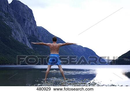 Stock Photo - Rear view of man exercising in lake . Fotosearch