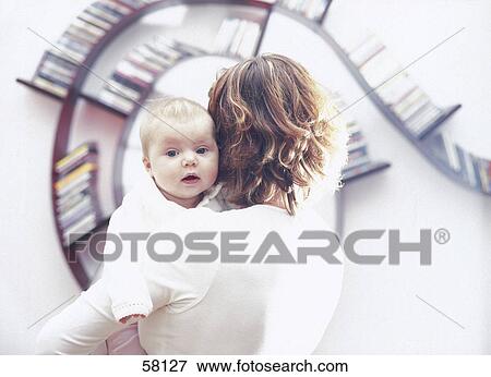 Rear view of woman carrying her baby in front of cd's rack View Large Photo Image Stock Photo - Rear view of woman carrying her baby in front of cd's rack . Fotosearch