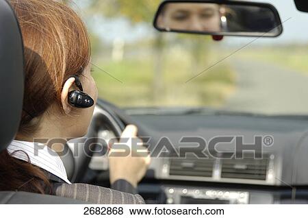 Rear view of woman using bluetooth while driving car View Large Photo Image Stock Photo - Rear view of woman using bluetooth while driving car . Fotosearch