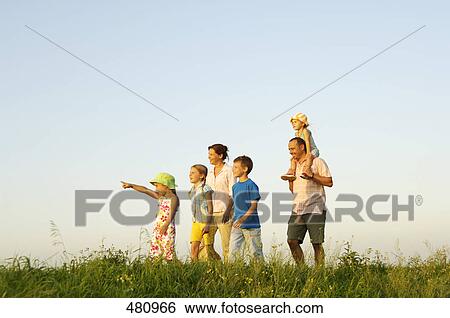 Stock Photograph - Side profile of family walking in field . Fotosearch