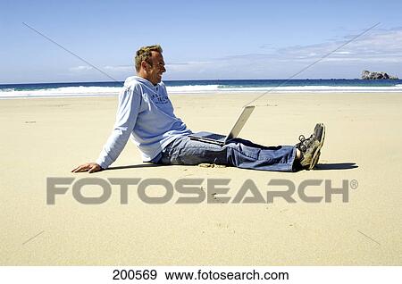 Side profile of man sitting with laptop on beach View Large Photo Image Stock Photo - Side profile of man sitting with laptop on beach . Fotosearch