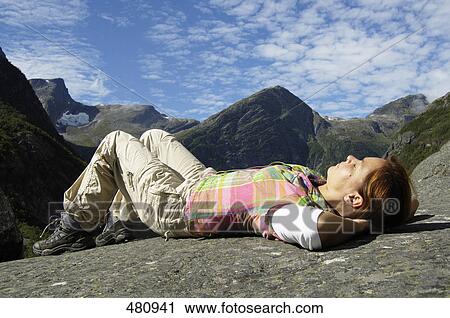 Stock Image - Side profile of mid adult woman resting on mountain . Fotosearch