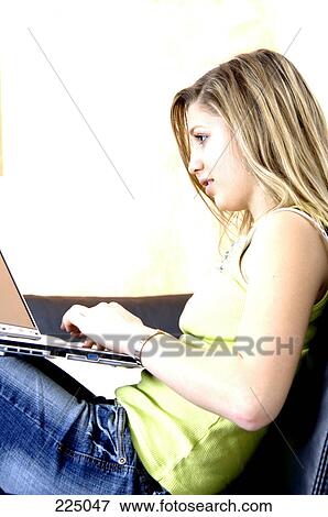 Stock Photo - Side profile of teenage girl using laptop on sofa . Fotosearch