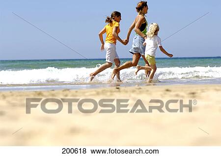 Side profile of woman running with her two daughters on beach View Large Photo Image Stock Photo - Side profile of woman running with her two daughters on beach . Fotosearch