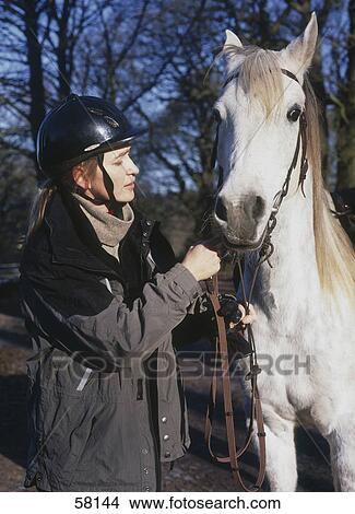 Side profile of young woman holding horse with rein View Large Photo Image Picture - Side profile of young woman holding horse with rein . Fotosearch