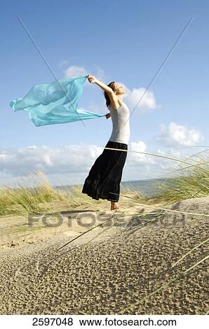 Side profile of young woman holding stole on beach View Large Photo Image Stock Photo - Side profile of young woman holding stole on beach . Fotosearch