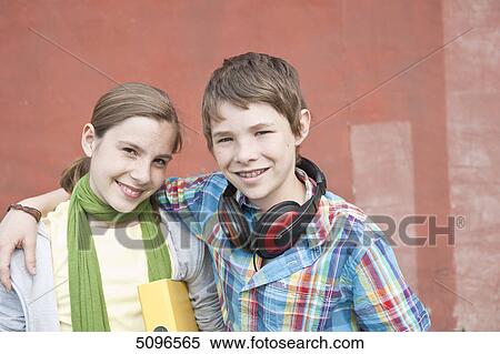Stock Photography - Smiling boy with headphones and girl with folder embracing . Fotosearch
