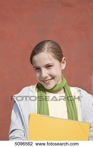 Smiling girl holding folder, portrait View Large Photo Image Stock Image - Smiling girl holding folder, portrait . Fotosearch