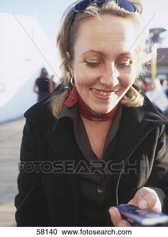 Smiling woman looking at mobile phone View Large Photo Image Stock Image - Smiling woman looking at mobile phone . Fotosearch