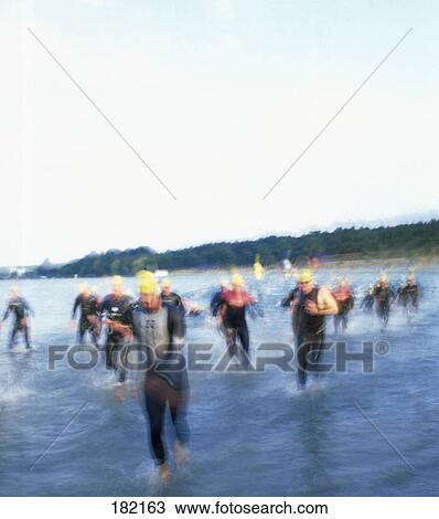 Stock Image - Swimmers running on beach . Fotosearch