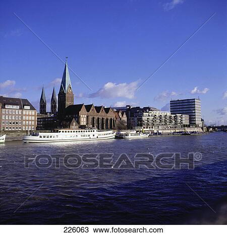 Stock Image - Tour boats at harbor with church in background, St. Martini Church, Lesum River, Germany . Fotosearch