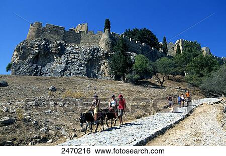 Stock Photograph - Tourists on donkeys in front of castle, Lindos, Rhodes, Dodecanese Islands, Greece . Fotosearch