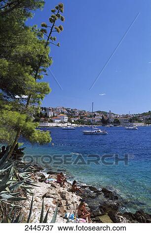 Stock Photo - Tourists sitting on coast, Hvar, Dalmatia, Croatia . Fotosearch
